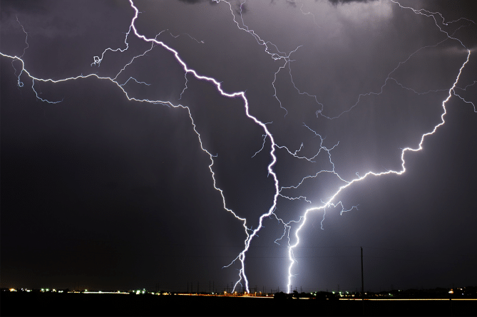 A bolt of lightning in a gray sky; one of the reasons power surge protection is a must.