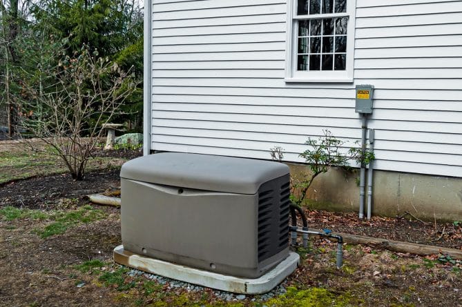 A whole house generator sitting outside a white Tennessee home.