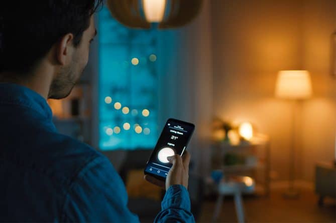 A man adjusting the light in his home using home lighting tips.